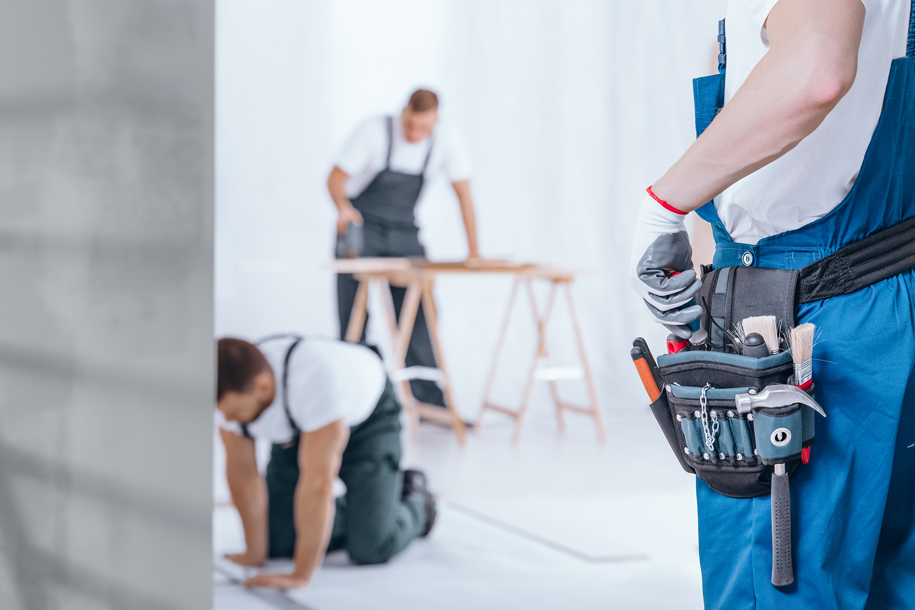 Professional architect in protective hardhat measuring wall with tape-line standing near step ladder construction safety and equipment during renovation process