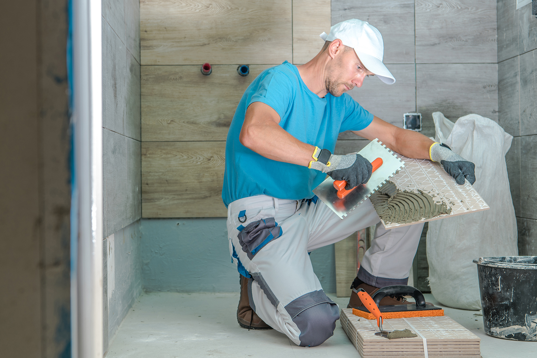 Professional architect in protective hardhat measuring wall with tape-line standing near step ladder construction safety and equipment during renovation process